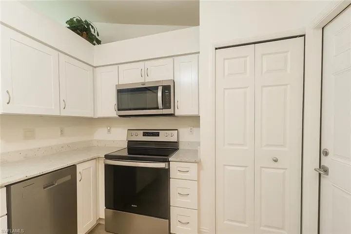 Kitchen with appliances with stainless steel finishes, light stone countertops, and white cabinets