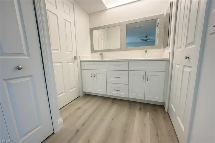 Full bath with double vanity, light wood-type flooring, a closet, and ceiling fan