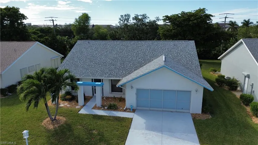 View of front of house featuring roof with shingles, a front yard, stucco siding, and concrete driveway