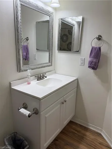 Bathroom with vanity, shower / tub combo with curtain, and dark wood-type flooring