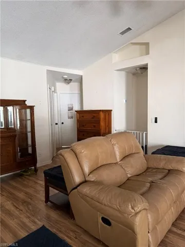Living room featuring dark wood-style floors, a textured ceiling, vaulted ceiling, and ceiling fan