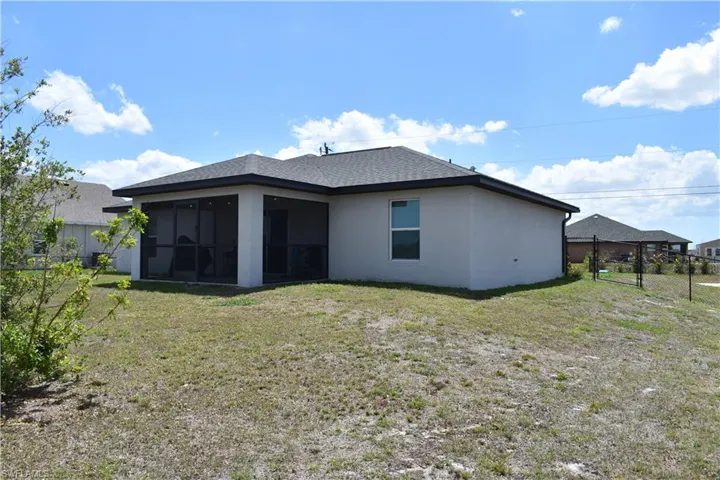 Back of house with a lawn, stucco siding, a sunroom, and fence
