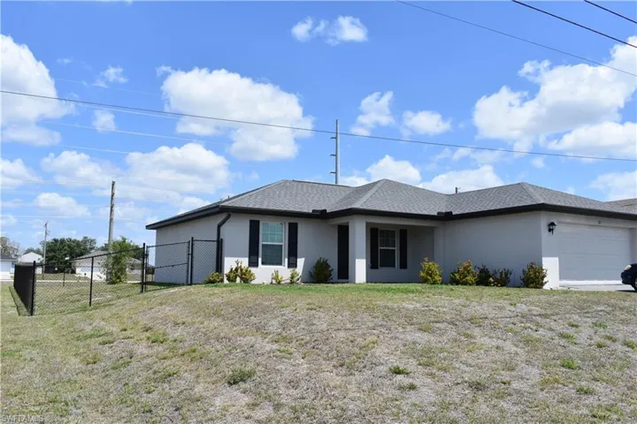 View of front facade featuring stucco siding, fence, an attached garage, a front lawn, and a shingled roof