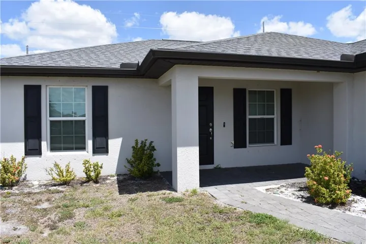 Entrance to property featuring stucco siding and roof with shingles