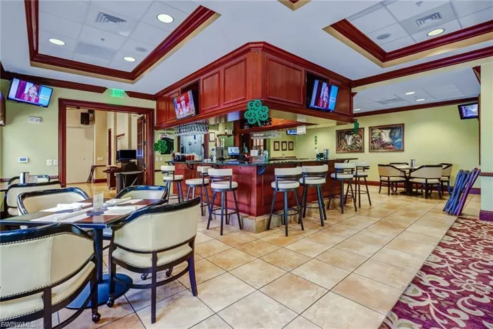Bar area with ornamental molding, dark brown cabinets, dark countertops, and recessed lighting