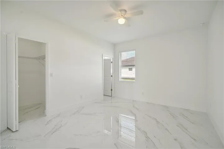 Unfurnished bedroom with ceiling fan, a closet, and a walk in closet
