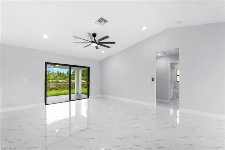 Spacious interior featuring marble-look tile flooring, vaulted ceilings, and a contemporary ceiling fan with integrated lighting