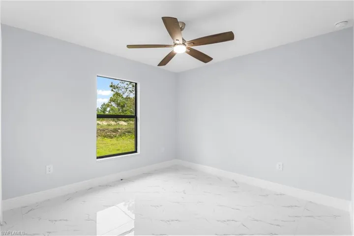 Spacious room featuring a ceiling fan with light, a single window with a dark frame, and light-toned walls