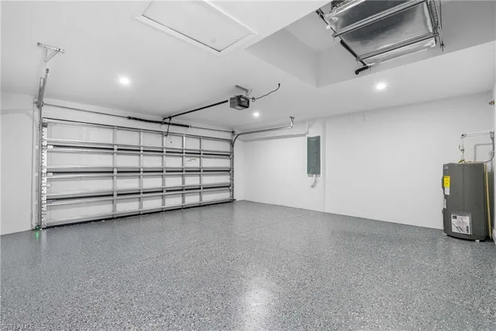 Spacious garage featuring a durable epoxy-coated floor, bright recessed lighting, and a paneled garage door with an automatic opener