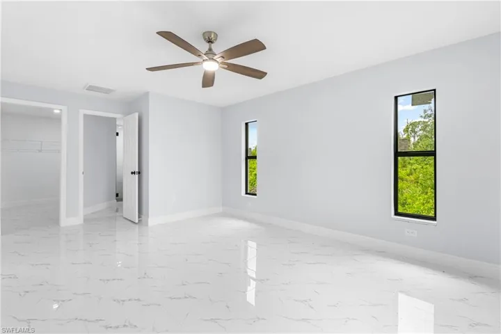 Spacious room featuring white tile flooring, light gray walls, and two vertical windows