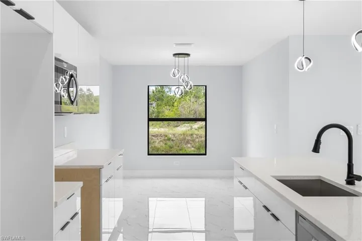 Open-concept kitchen featuring white cabinetry, light-toned countertops, and contemporary pendant lighting
