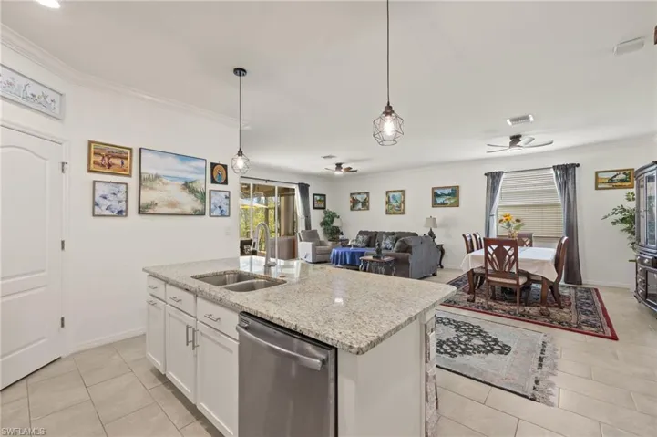 Kitchen with dishwasher, a double sink, ceiling fan, ornamental molding, and light tile patterned floors