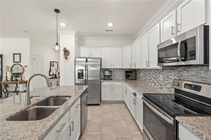 Kitchen featuring stainless steel appliances, a double sink & white cabinets.