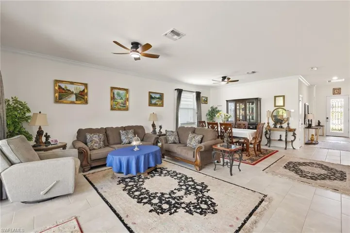 Living area featuring ceiling fan, crown molding, and light tile patterned flooring