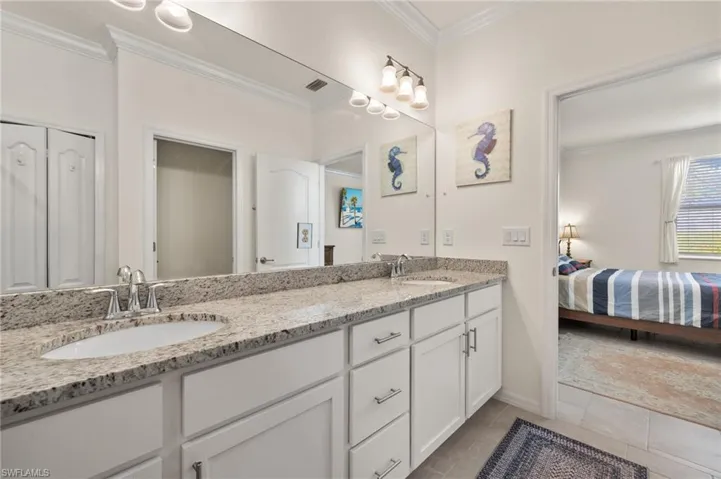 Ensuite bathroom with double vanity, crown molding, tile patterned flooring, and baseboards