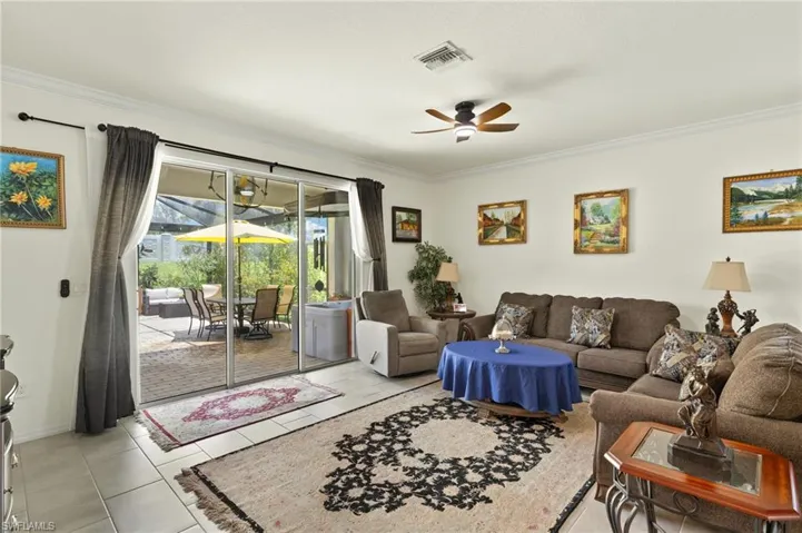 Living area featuring ornamental molding, ceiling fan, light tile patterned floors, and baseboards