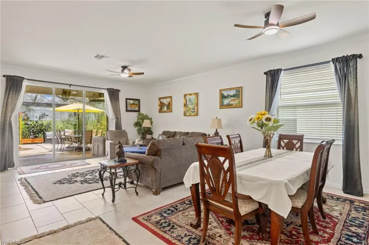 Dining area with a ceiling fan, ornamental molding, and light tile patterned floors