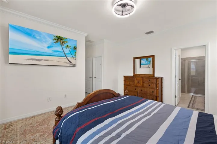 Bedroom with crown molding, baseboards, and ensuite bath