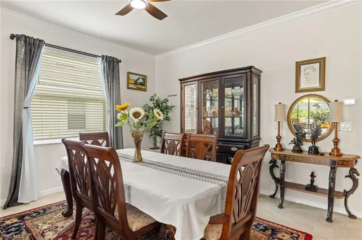Dining room featuring ceiling fan, ornamental molding, light tile patterned floors, and baseboards