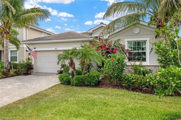 View of front of property featuring decorative driveway, an attached garage, a front lawn, and stucco siding