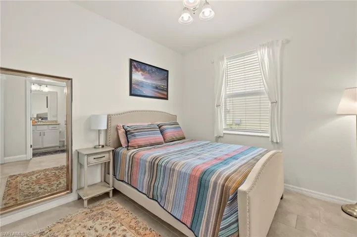 Bedroom with baseboards, light tile patterned floors, and ensuite bathroom