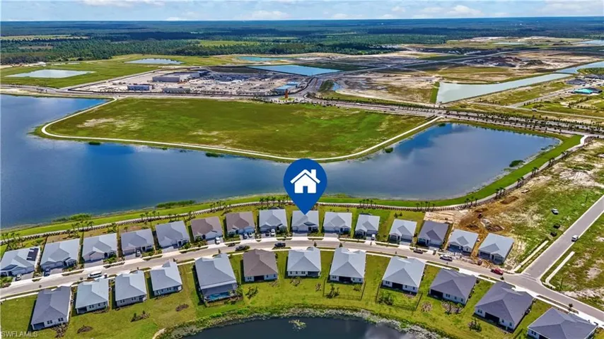Aerial perspective of a single-family residence situated in a planned community featuring water frontage, paved street access, and expansive green space