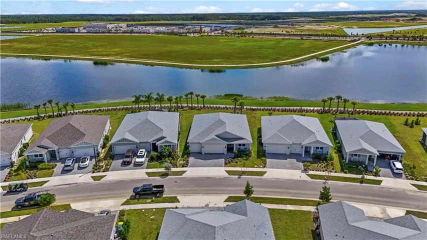 Aerial perspective of residential properties featuring hip-roof architecture, concrete driveways, and expansive water frontage