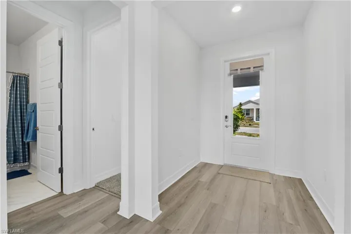 Entryway featuring wood-finish flooring, a white paneled door with glass inlay, and recessed ceiling lighting