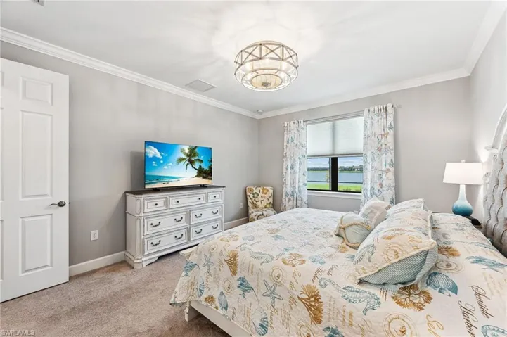 Carpeted bedroom featuring ornamental molding and an inviting chandelier