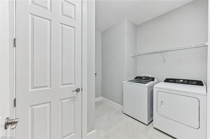 Clothes washing area featuring separate washer and dryer and light tile patterned floors