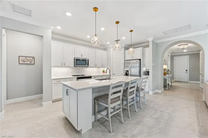 Kitchen featuring a kitchen island with sink, appliances with stainless steel finishes, crown molding, and sink