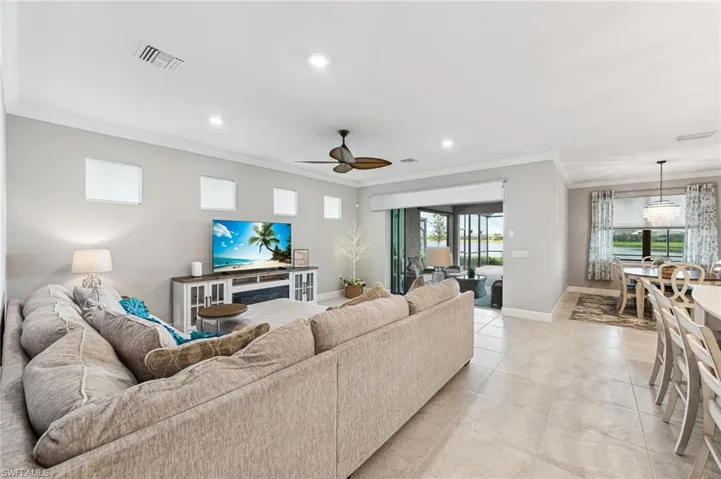 Living room featuring ceiling fan, light tile patterned floors, and ornamental molding