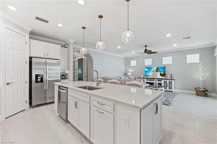 Kitchen with appliances with stainless steel finishes, an island with sink, sink, ceiling fan, and white cabinets