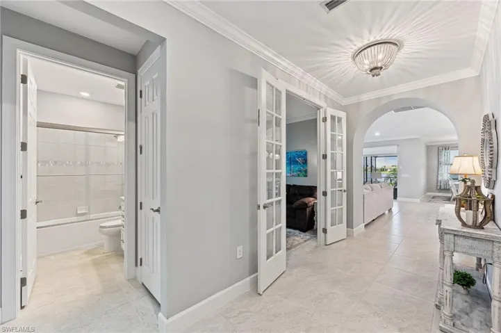 Hall with ornamental molding, light tile patterned floors, and french doors