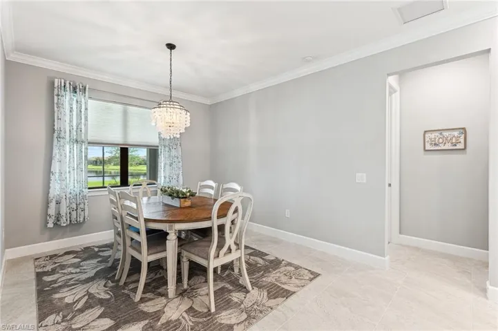 Dining room with ornamental molding, light tile patterned floors, and an inviting chandelier