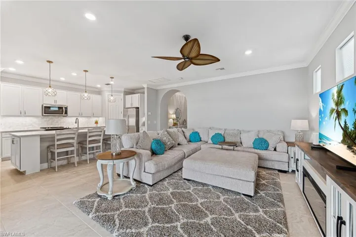 Living room with crown molding, sink, and ceiling fan