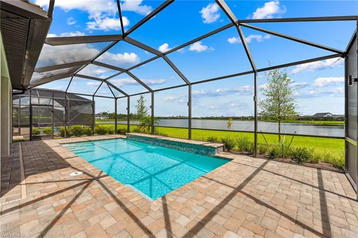 View of pool featuring a patio area, glass enclosure, and a water view