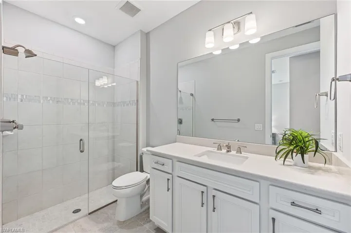 Bathroom with an enclosed shower, tile patterned flooring, toilet, and vanity