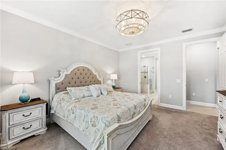 Carpeted bedroom featuring ensuite bathroom and crown molding