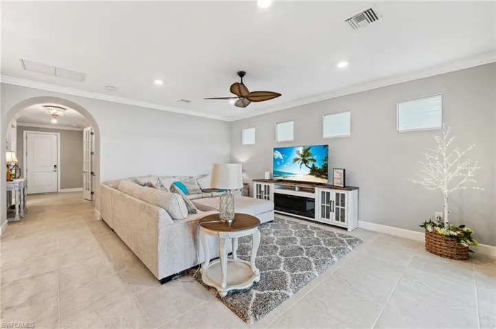 Living room featuring crown molding, ceiling fan, and light tile patterned floors