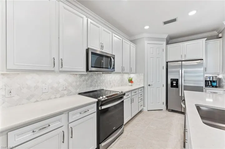 Kitchen featuring appliances with stainless steel finishes, tasteful backsplash, and white cabinets