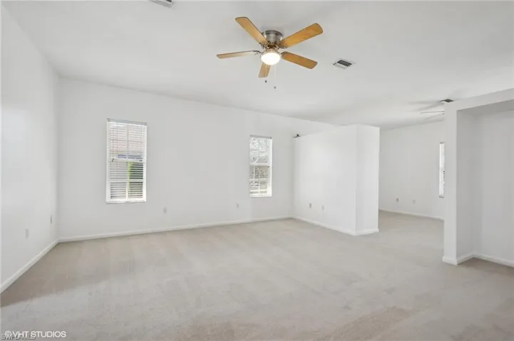 Spacious primary bedroom featuring a separated sitting area, a new ceiling fan, new carpet