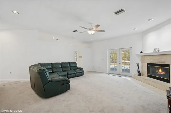 Living area with carpet floors, a tile fireplace, french doors, and visible vents