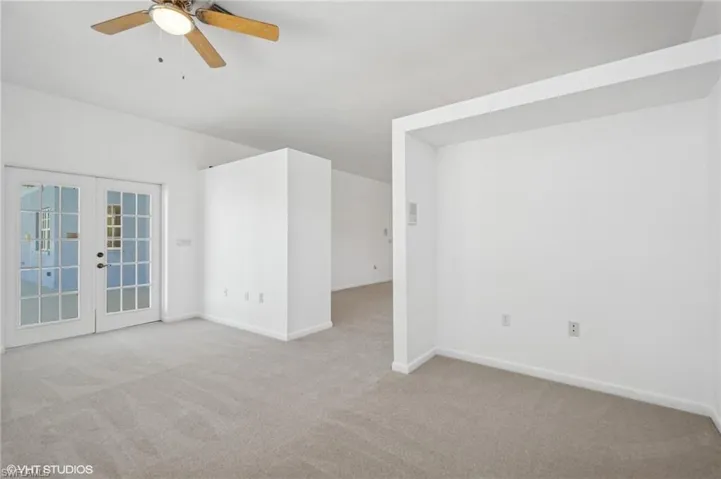 Carpeted empty room featuring french doors, ceiling fan, and baseboards