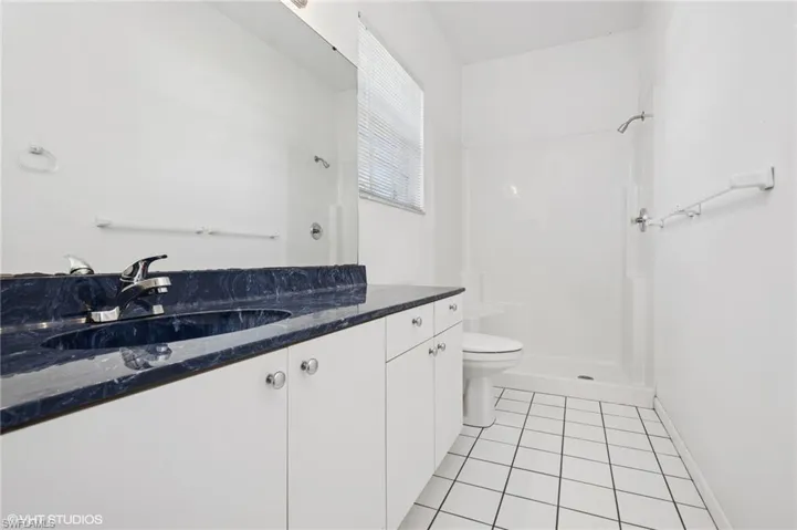 Bathroom featuring toilet, tile patterned flooring, a shower, and vanity