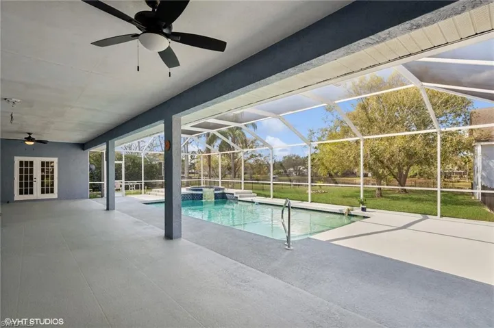 View of swimming pool with a lanai, a patio area, a ceiling fan, and french doors