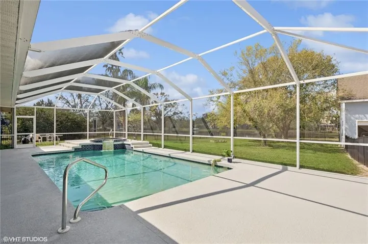 View of swimming pool with a pool with connected hot tub, a lanai, a patio, and a lawn