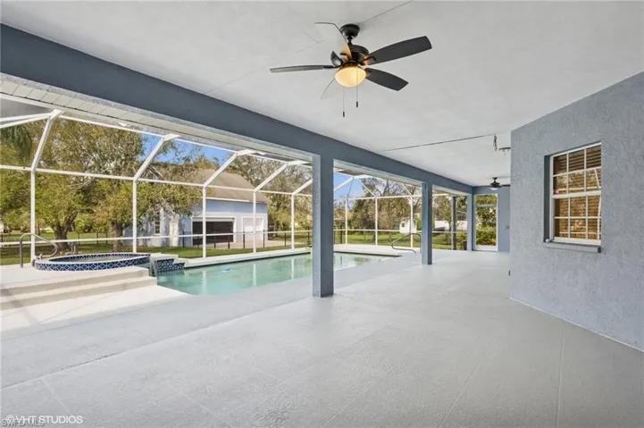 View of swimming pool with a lanai, ceiling fan, a pool with connected hot tub, and a patio