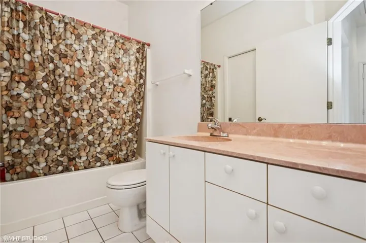 Bathroom with vanity, shower / tub combo, tile patterned flooring, and toilet