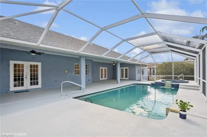 View of swimming pool featuring a pool with connected hot tub, french doors, a patio, and ceiling fan